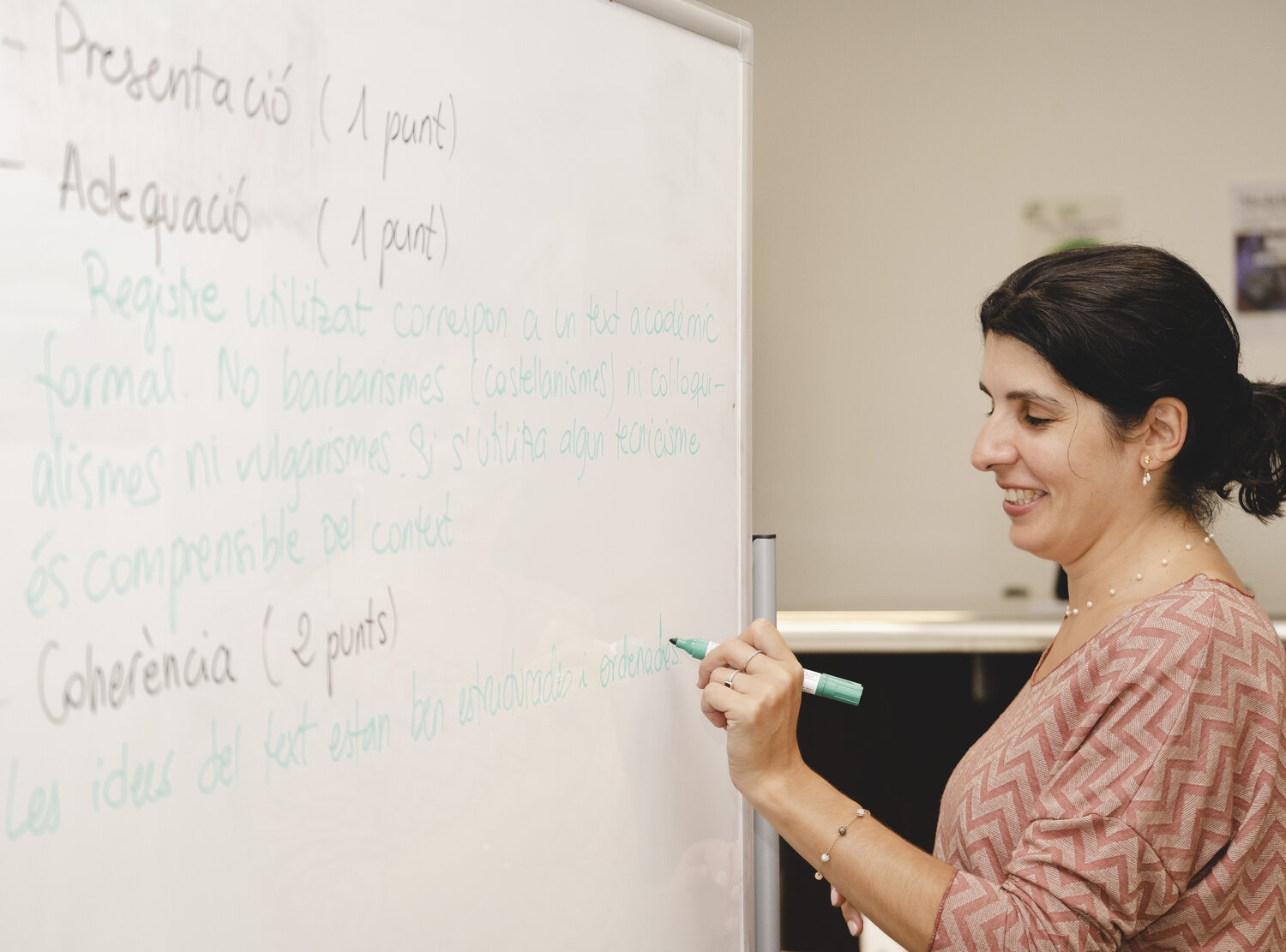 Sara escribiendo en la pizarra los criterios con los que se puntúa un examen oficial: presentación, adecuación y coherencia, con los puntos de cada uno